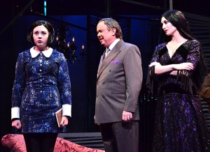 Gomez Addams (Eddie Curry, center) is caught between honoring the wishes of his daughter Wednesday (Samantha Russell, left) and wife Morticia (Erin Cohenour) in a scene from 